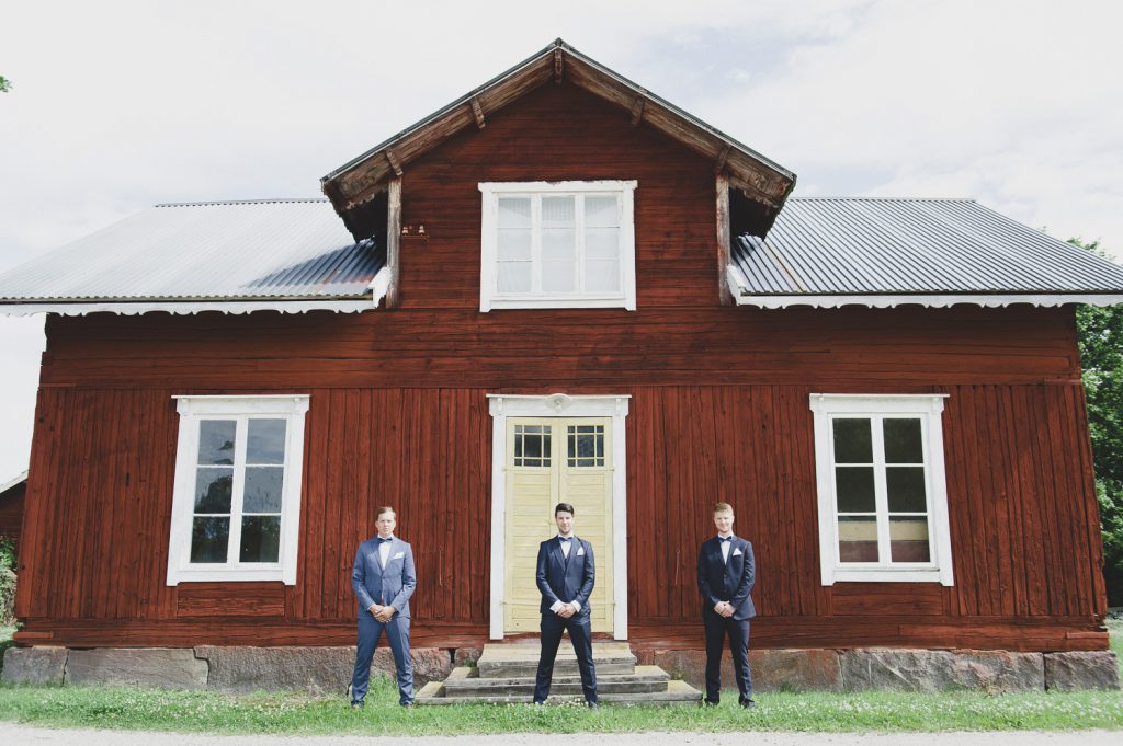 Brudgrum och hans två bestman framför ett rött hus i Hedsta, Veckholm