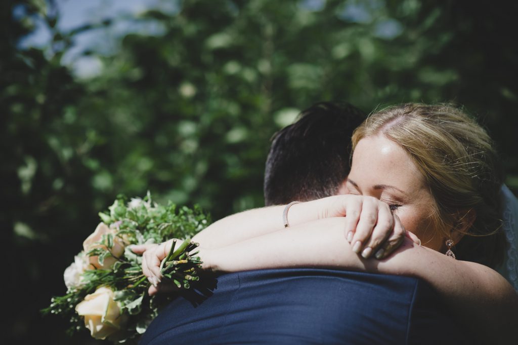 Bruden kramar om brudgummen med buketten
